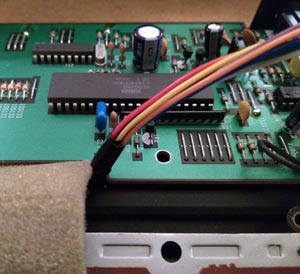 With various electronic components such as resistors, capacitors, and integrated circuits, a close-up view captures the details of a green printed circuit board (PCB). On one side, a bundle of multicolored wires is connected to the board.