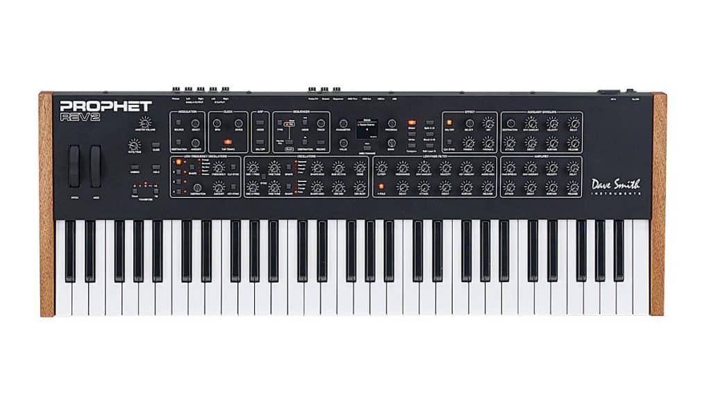 A sleek, modern design characterizes the Prophet Rev2 synthesizer, featuring 5 octaves of keys. On the left side, it boasts pitch and modulation wheels, while various control knobs and buttons adorn the top panel. Wooden side panels complete its sophisticated look.